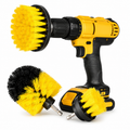 Yellow and black power drill with three brush attachments on a white background